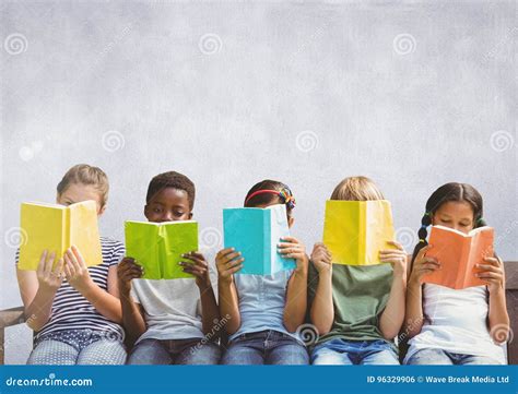 Group Of Children Sitting And Reading In Front Of Grey Background Stock