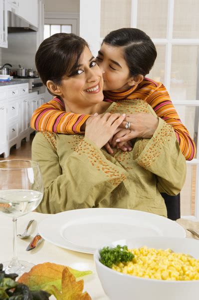 Mother And Daughter At Thanksgiving Table With Daughter Kissing And