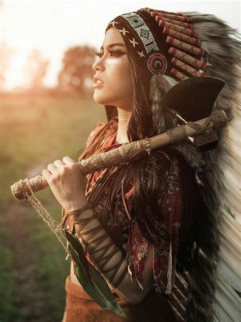A Woman Dressed In Native American Clothing Holding A Stick