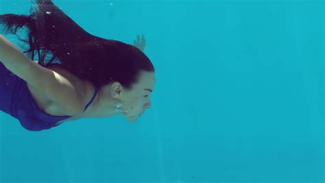 Brunette Woman Swimming Underwater In Blue Bathing Suit In Slow Motion