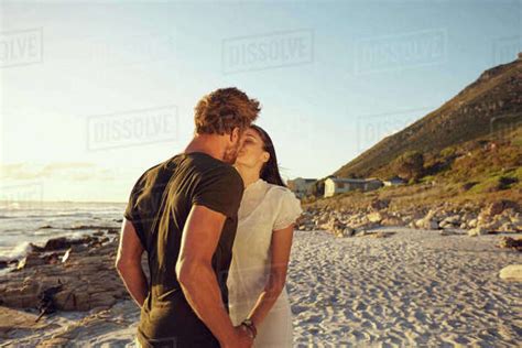 Shot Of Young Couple Kissing At Sunset On Beach Loving Couple On Beach Sharing An Intimate