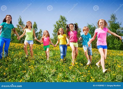 Happy Children Run And Hold Hands In Green Field Stock Photo Image Of