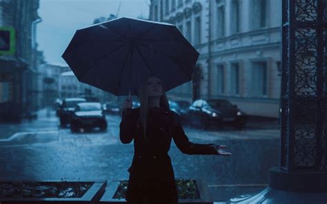 Обои на рабочий стол Девушка с зонтом стоит на улице города под дождем фотограф Khusen Rustamov