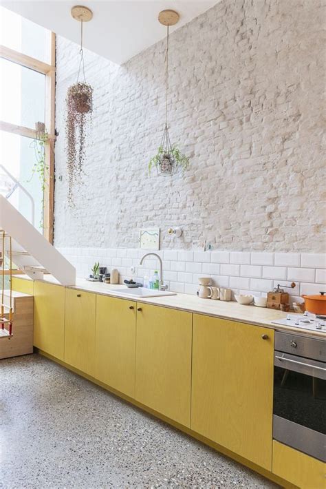The brick wall adds a layer of visual warmth. 25 Yellow And White Kitchens That Raise The Mood - DigsDigs