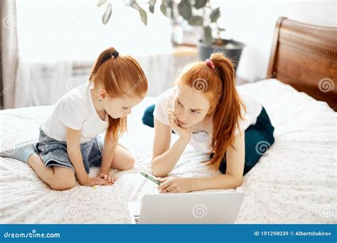 Red Haired Mom And Her Daughter Lying On Bed At Home While Looking At Laptop Stock Image Image