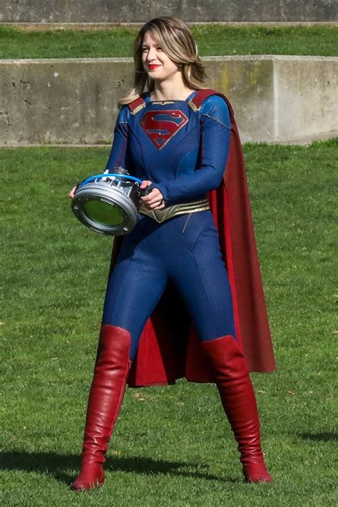 A Woman In A Superman Costume Holding A Football