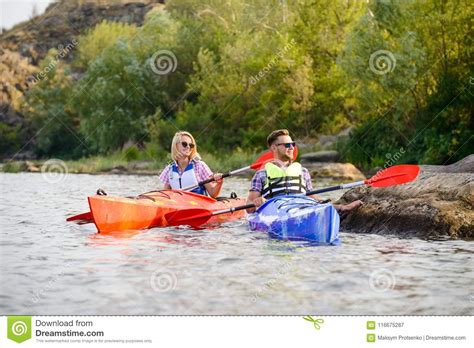 Young Happy Couple Paddling Kayaks On Beautiful River Or Lake Stock