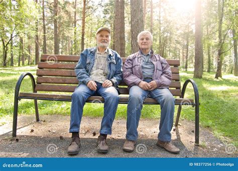 Two Elderly Men Are Sitting On A Park Bench Elderly Man Dressed In