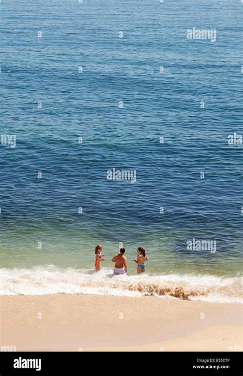Three People On A Beach At The Waters Edge On A Summer Holiday Vale