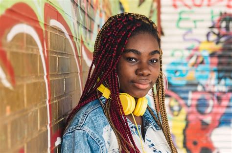 premium photo exotic black girl with colored braids in her hair leaning on a graffiti wall