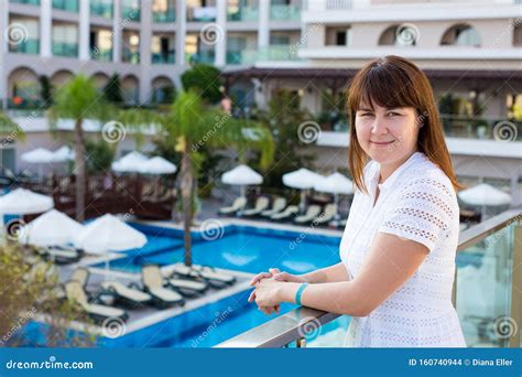 Young Woman In White Dress Posing On Balcony Of Modern Hotel Stock