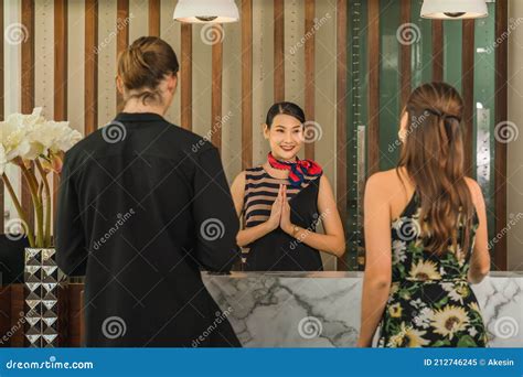 Thai Hotel Receptionist Welcome And Greeting Hotel Guest Couple With Thai Wai Stock Image