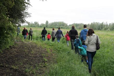 The Group With Adults And Children Walk And Follow The Guide In The
