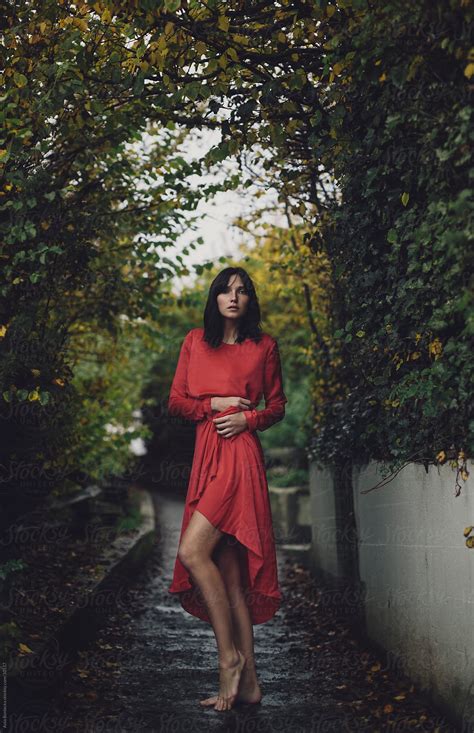a woman in a red dress standing in a green passage by stocksy contributor a model