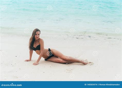 Model In Black Swimsuit Lying On White Sandy Beach Girl Sunbathes And