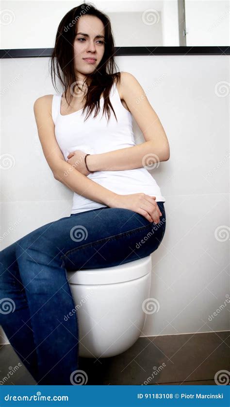 Young Woman Sitting On Toilet In Public Bathroom Portrait