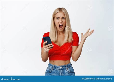 Angry And Frustrated Blond Girl Screams Holds Mobile Phone And Shouts