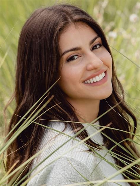 A Woman Is Smiling While Standing In Tall Grass