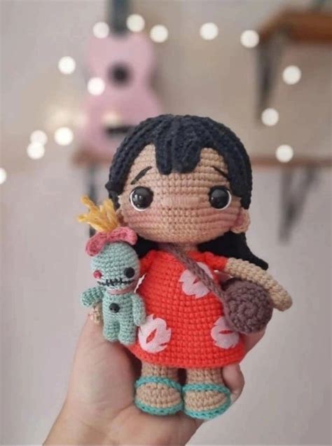 A Small Crocheted Doll Holding A Stuffed Animal In Its Right Hand
