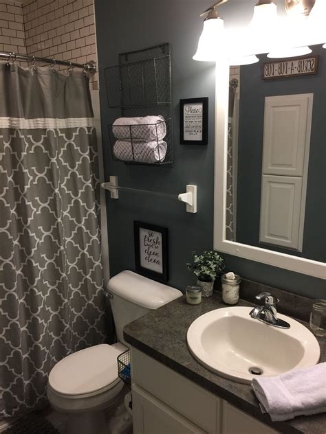A White Toilet Sitting Next To A Bathroom Sink Under A Mirror With Lights On It