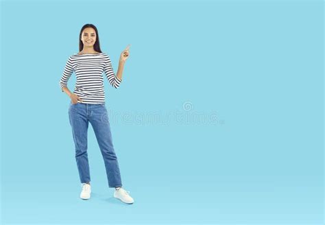 Smiling Young Woman Pointing Her Finger To Empty Space Stock Photo