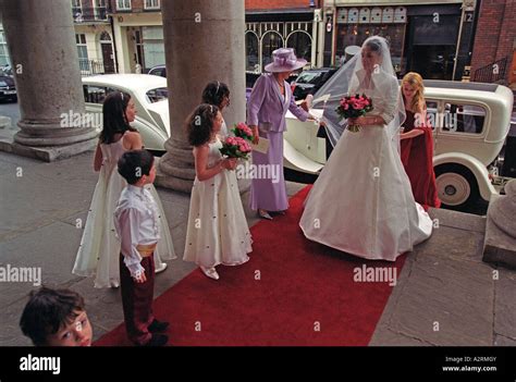 Bride Arrives At Church Greeted By Her Bridesmaids And Pageboys Stock