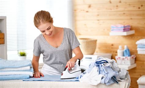 Happy Woman Housewife Ironing Clothes In Laundry At Home Stock Photo