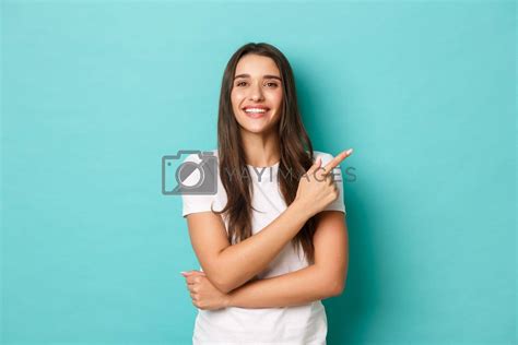Cheerful Brunette Girl In White T Shirt Smiling Pleased And Pointing Fingers At Upper Right