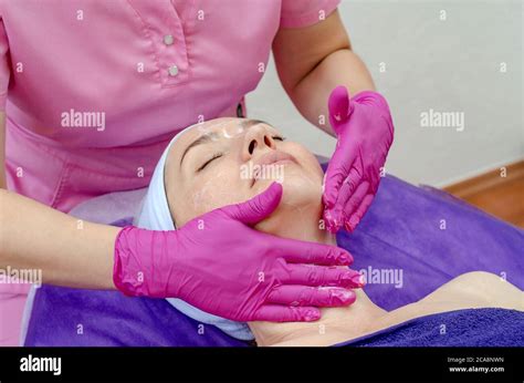 Cosmetologist Doctor Applies Cream To Woman Face In Beauty Salon Preparation For The Procedure