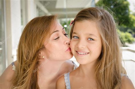 Mother Kissing Her Daughter In The Cheek Stock Photo Martinbalo
