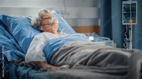 hospital ward portrait of beautiful elderly woman wearing oxygen mask sleeping in bed fully