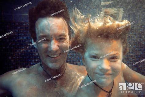 Father And Son Swimming Underwater In Swimming Pool Stock Photo