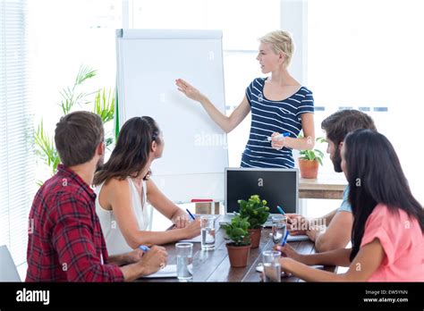 Casual Businesswoman Giving Presentation To Her Colleagues Stock Photo
