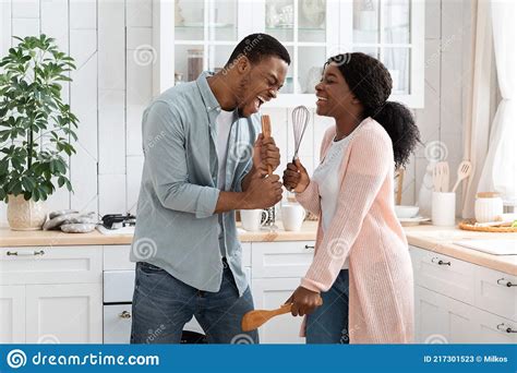 domestic concert funny black spouses fooling in kitchen singing with utensils stock image