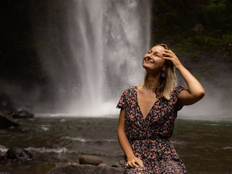 Young Caucasian Woman Sitting On The Rock And Enjoying Waterfall