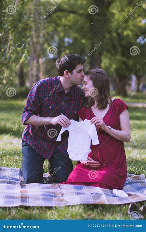 Young Couple Soon To Be Parents Holding A Little Baby Cloth Together