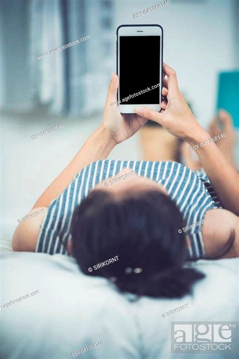 Asian Woman Rest On Bed Hand Holding Smart Phone With Blank On Screen Stock Photo Picture