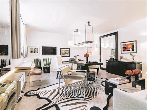 The band coffee table maintains the perfect balance of bold forms and mixed materials, combining a stainless steel plinth base finished in mirrored brass, and contrasting snow white lacquer top; Kelly Hoppen is celebrating 40 years of transforming rooms