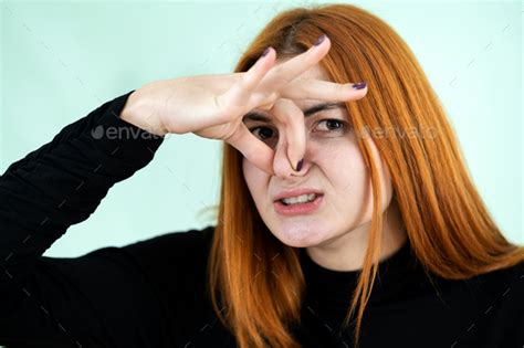 Funny Pretty Redhead Girl Showing Bad Smell Sign With Her Fingers Stock