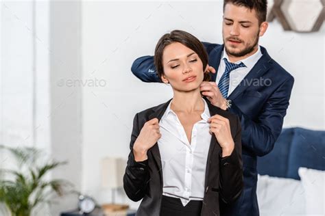 Boyfriend Helping Girlfriend Wearing Jacket In Morning At Home Stock