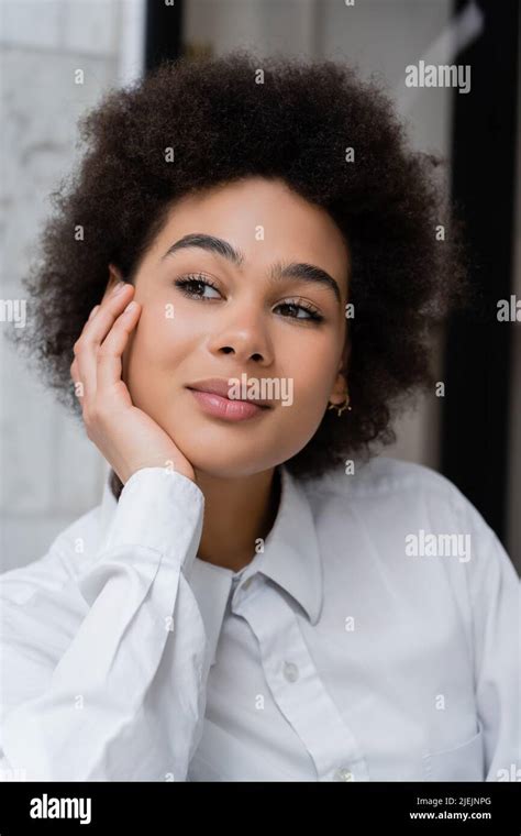 Portrait Of Dreamy And Curly African American Woman In White Shirt With
