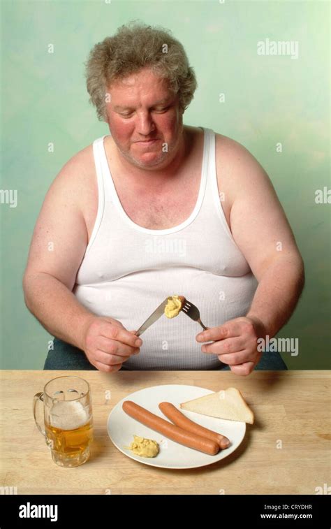 Fetter Mann im Unterhemd essen zwei Würstchen mit Senf Stockfoto Bild Alamy