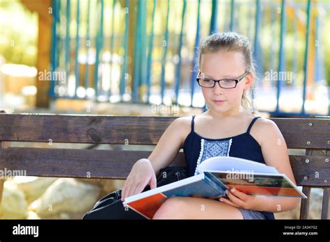 Portrait Of Cute Pensive Little Girl With Glasses Sitting On The Wooden