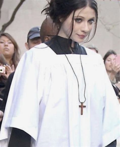 A Woman In A Priests Outfit Walking Down The Street With People Behind Her