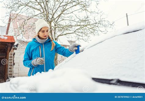 Woman Scraping Off Ice From Front Window Of Her Car In Winter Stock