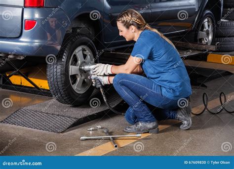 Female Mechanic Fixing Car Tire With Pneumatic Wrench Stock Photo