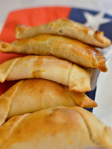 Empanadas chilenas tradicionales típicos con carne, cebolla, huevos y aceitunas en la tabla de cortar rústica mapuche en el fondo de madera azul. Las mejores empanadas de Santiago de Chile para las ...