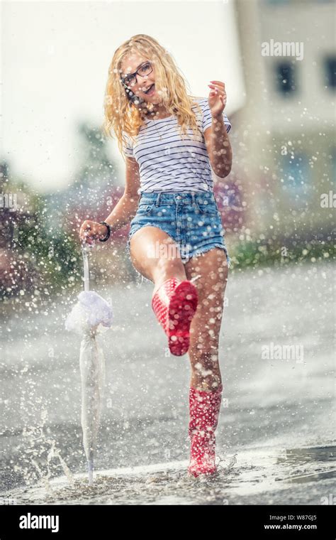 cheerful girl jumping with white umbrella in dotted red galoshes hot summer day after the rain