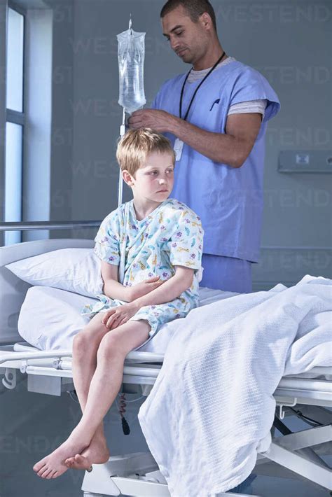 Male Nurse Adjusting Boy Patients Intravenous Drip In Hospital Children