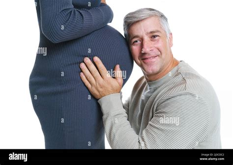 happy husband with closed eyes listening to his pregnant wife belly against white background